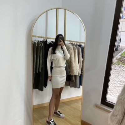 Pessoa em espelho a usar saia e top bege claro com sapatilhas coloridas