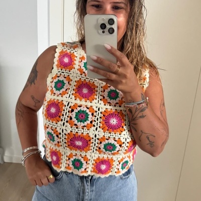 Top de croché floral em cores vivas e calças de ganga claras numa selfie interior