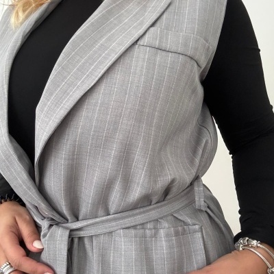 Colete cinzento riscado com cinto e bolso com aba sobre camisola preta