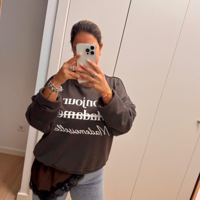 Pessoa a tirar selfie de sweat cinza escuro com texto branco e jeans claros