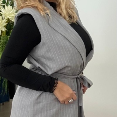 Mulher a usar colete cinza risca de giz com cinto e calças combinadas