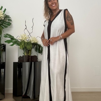 Vestido longo branco com faixas pretas laterais num ambiente interior com plantas