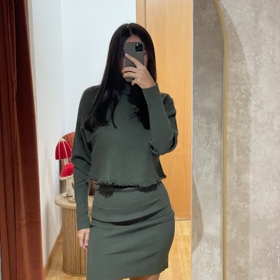 Conjunto de saia e camisola verde escura em ambiente interior com espelho