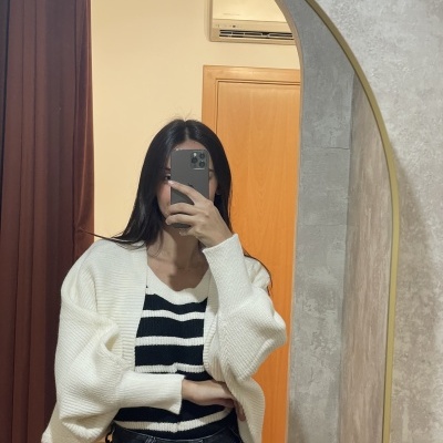 Casaco branco de malha canelada com camisola às riscas pretas e brancas numa mulher à frente de um espelho