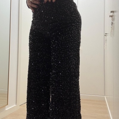 Calças pretas com lantejoulas usada com top vinho