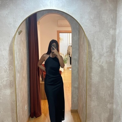 Vestido longo preto de alças num espelho oval com moldura dourada