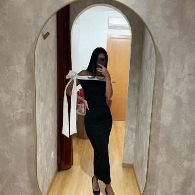 Vestido preto longo com laço branco no ombro refletido em espelho oval