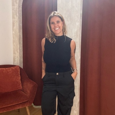 Mulher com roupa preta em ambiente interno com arcos cor ferrugem e poltrona similar