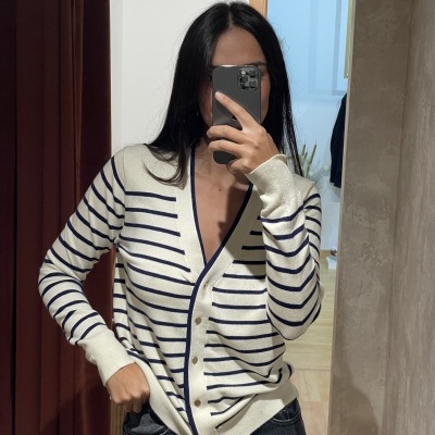 Carteado branco com riscas azuis horizontais e botões brancos usado por pessoa