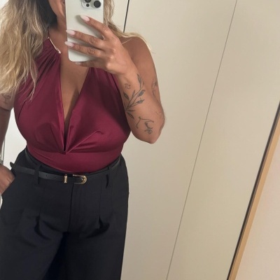 Top vinho acetinado com calças pretas e cinto refletido em espelho