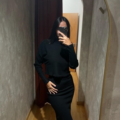 Vestido preto justo de malha com gola alta e barra irregular em selfie no espelho