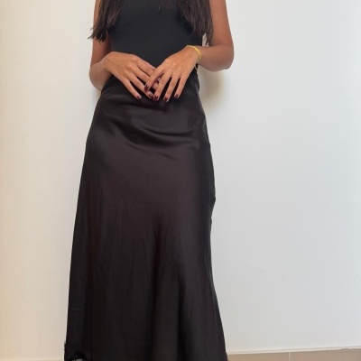 Saia preta longa de tecido acetinado com barra de renda preta detalhada e top preto sem mangas