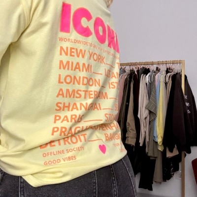 T-shirt amarela com texto colorido nas costas e calças de ganga cinzentas vista de lado