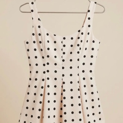 Top feminino branco com bolinhas pretas pendurado num cabide