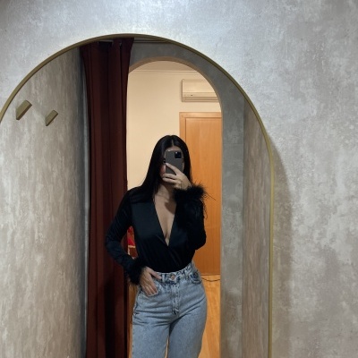 Mulher a tirar selfie num espelho com top preto e calças de ganga azul