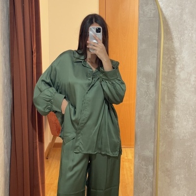 Pessoa a usar conjunto de pijama verde escuro refletido num espelho com moldura dourada