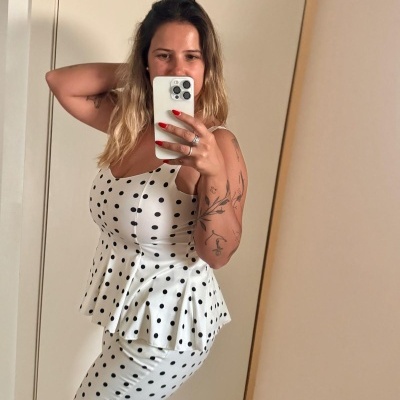 Mulher com conjunto branco de bolinhas pretas a tirar selfie em espelho