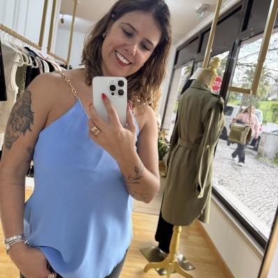 Top azul claro com alças de corrente dourada usado por mulher em loja