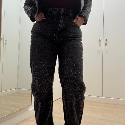 Calças pretas com pontos brancos, casaco preto de pele e botas prateadas num quarto com roupeiro branco