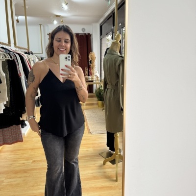 Pessoa vestindo blusa preta sem mangas e calças jeans flare cinza numa loja de roupas