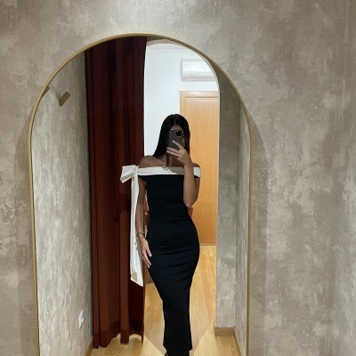Mulher com vestido preto e branco a tirar selfie num espelho arched