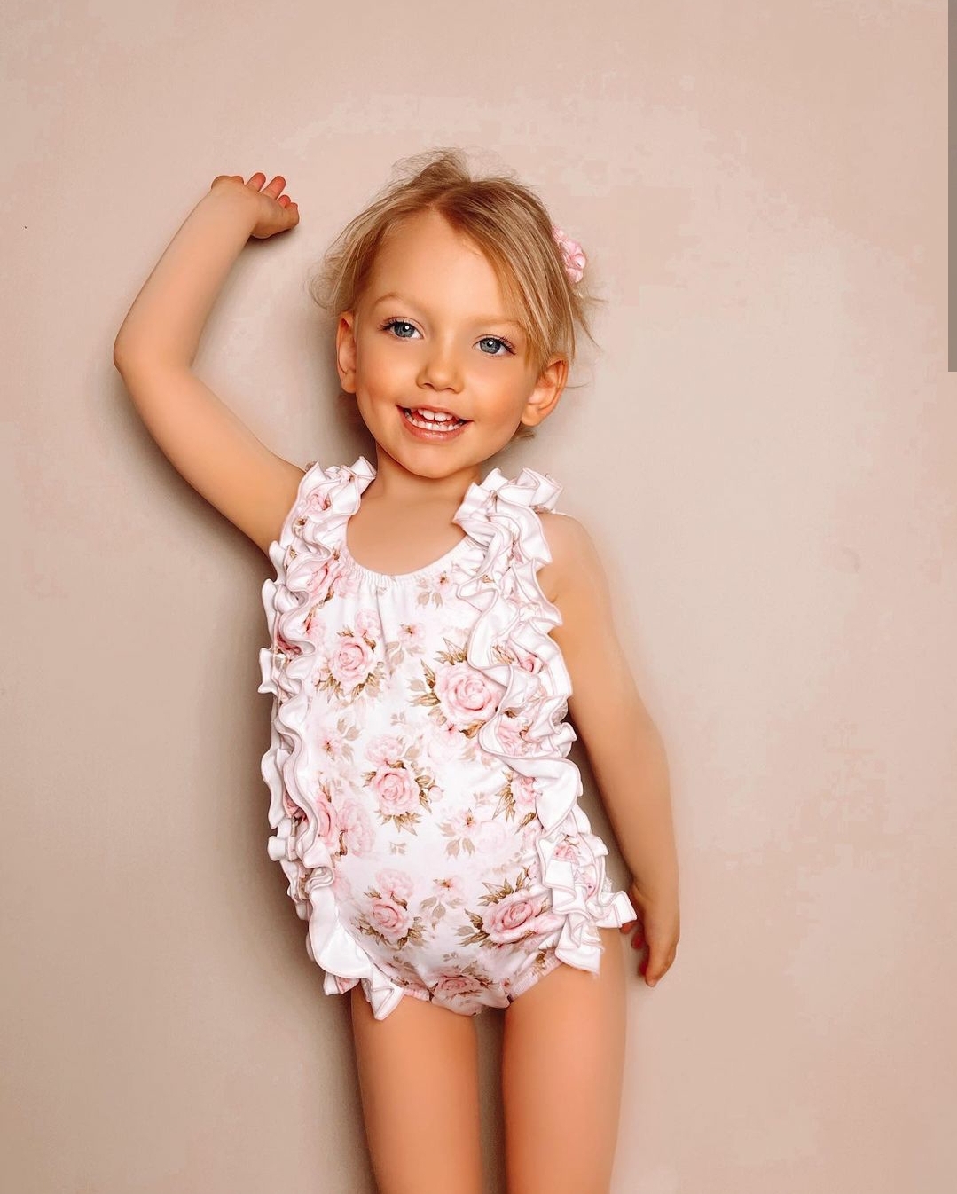 Fato de banho floral rosa e branco para menina com folhos, criança loira a sorrir