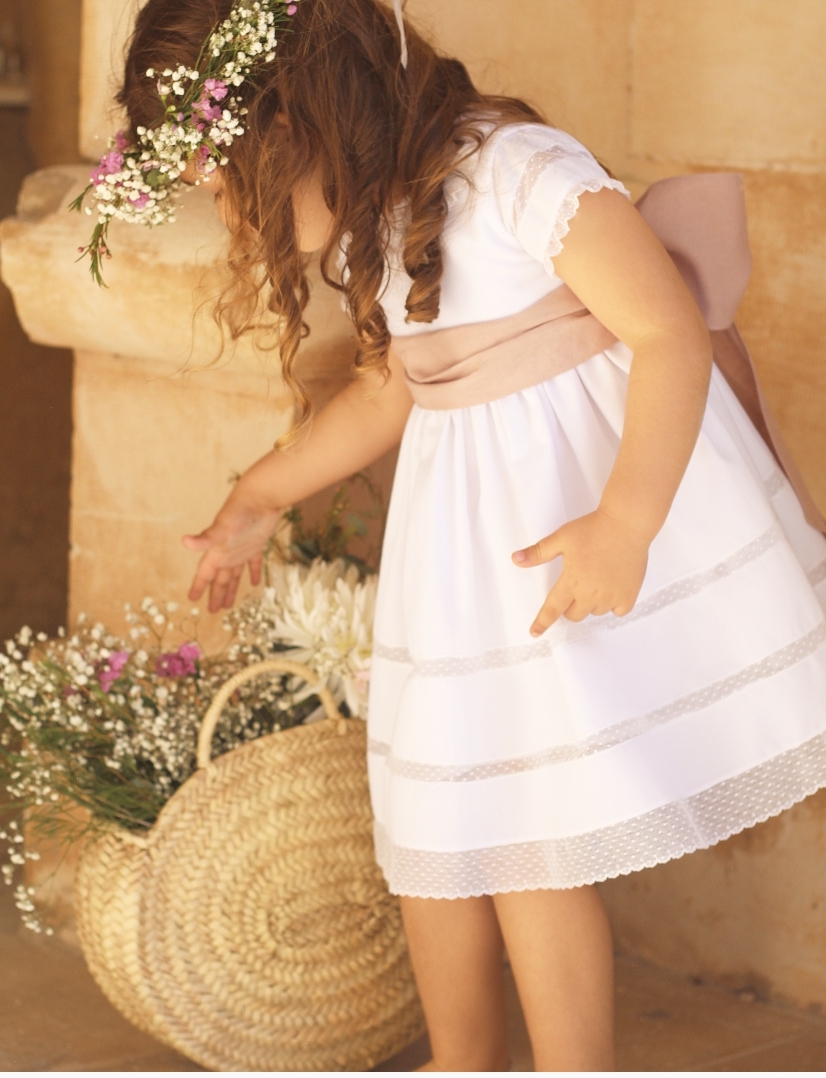 Vestido branco de criança com faixa bege e coroa de flores naturais
