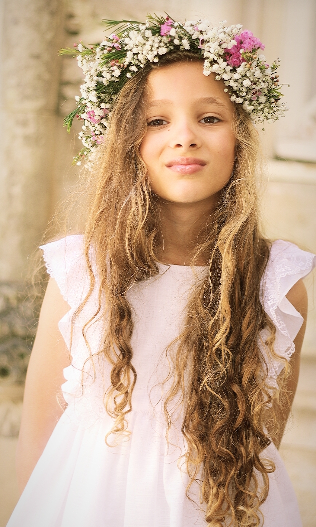 Menina com vestido branco e coroa de flores com flores brancas e rosas