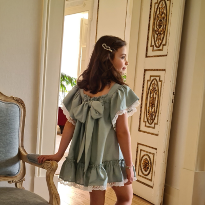 Criança com vestido verde-água de costas em sala clássica