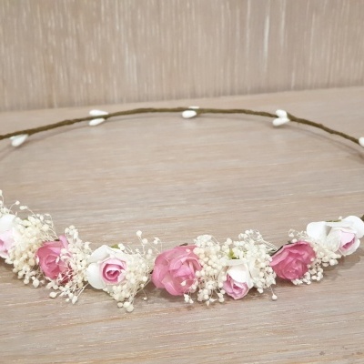 Coroa de flores rosa e brancas com base de ramo castanho sobre madeira clara