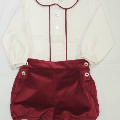 Conjunto de bebé com camisa branca de mangas compridas e calções vermelhos de veludo.