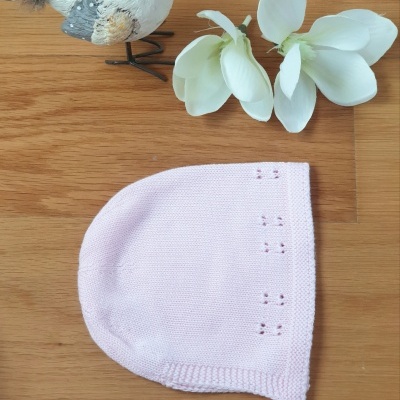 Gorro para bebé rosa em malha com flor branca artificial e pássaro decorativo sobre madeira clara
