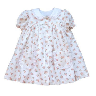 Vestido infantil branco com flores cor-de-rosa e verdes, gola branca bordada, botões frontais e bolsos com renda.