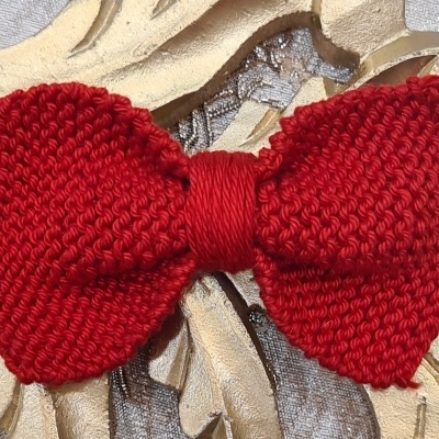 Gravata borboleta vermelha tricotada sobre fundo decorativo dourado