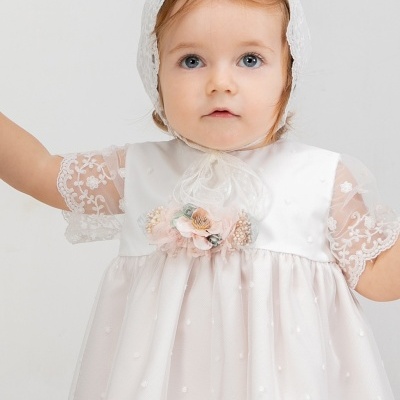 Bebé com vestido branco de renda e capuz de renda em fundo branco