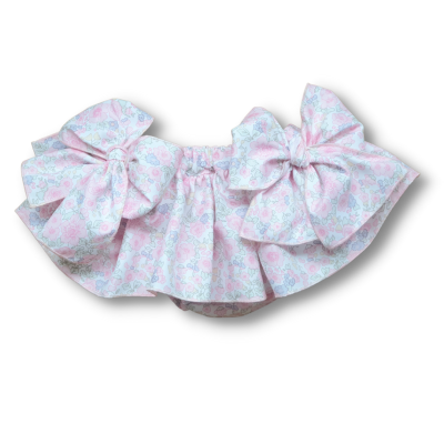 Peça de roupa infantil com padrão floral e dois grandes laços