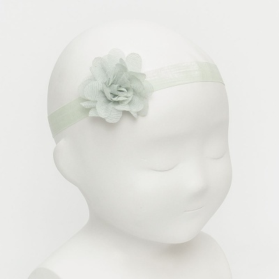 Faixa de cabelo verde claro com flor em tecido num manequim branco