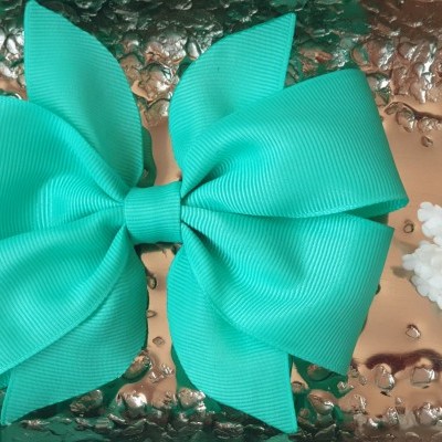 Laço azul turquesa sobre superfície metálica com flores