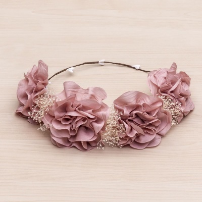 Coroa de flores artificiais rosa claro com pequenos detalhes brancos, sobre madeira clara