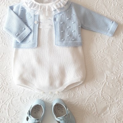 Conjunto de roupa de bebé branca e azul com sapatos azuis