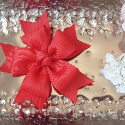 Laço vermelho sobre superfície metálica com flores ao lado