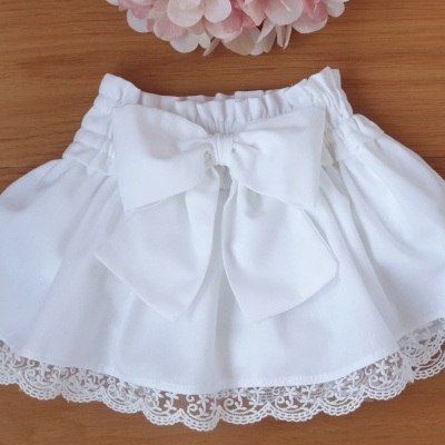 Saia branca com renda e laço em fundo de madeira