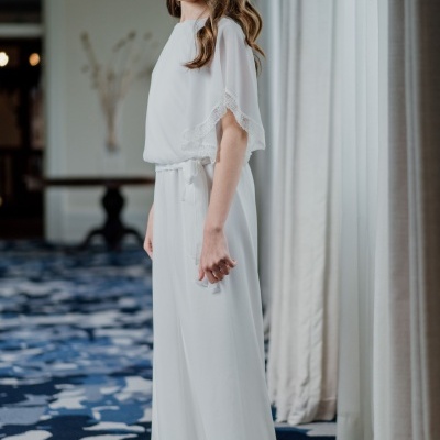 Rapaz vestida com fato branco de tecido fluido e grinalda de flores brancas