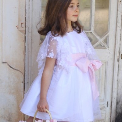 Menina com vestido branco e laço rosa segurando cesta com flores rosa