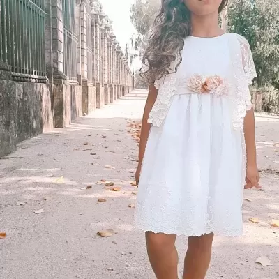 Vestido branco infantil com renda e flores decorativas em parque