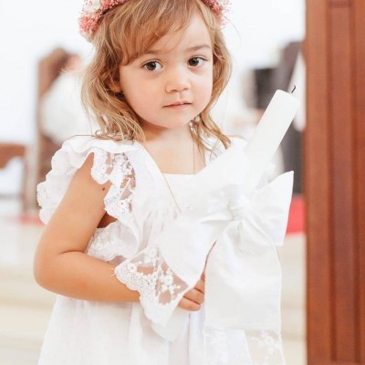 Menina com vestido branco e vela decorada com laço branco