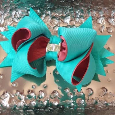 Laço de cabelo azul turquesa e vermelho sobre superfície metálica texturizada