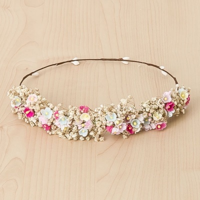 Tiara com flores artificiais coloridas e raminhos secos em fundo de madeira