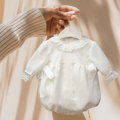 Vestido de bebé branco com gola e mangas de renda pendurado num cabide