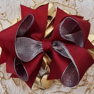 Laço decorativo vermelho e cinzento sobre fundo bege com padrão floral dourado